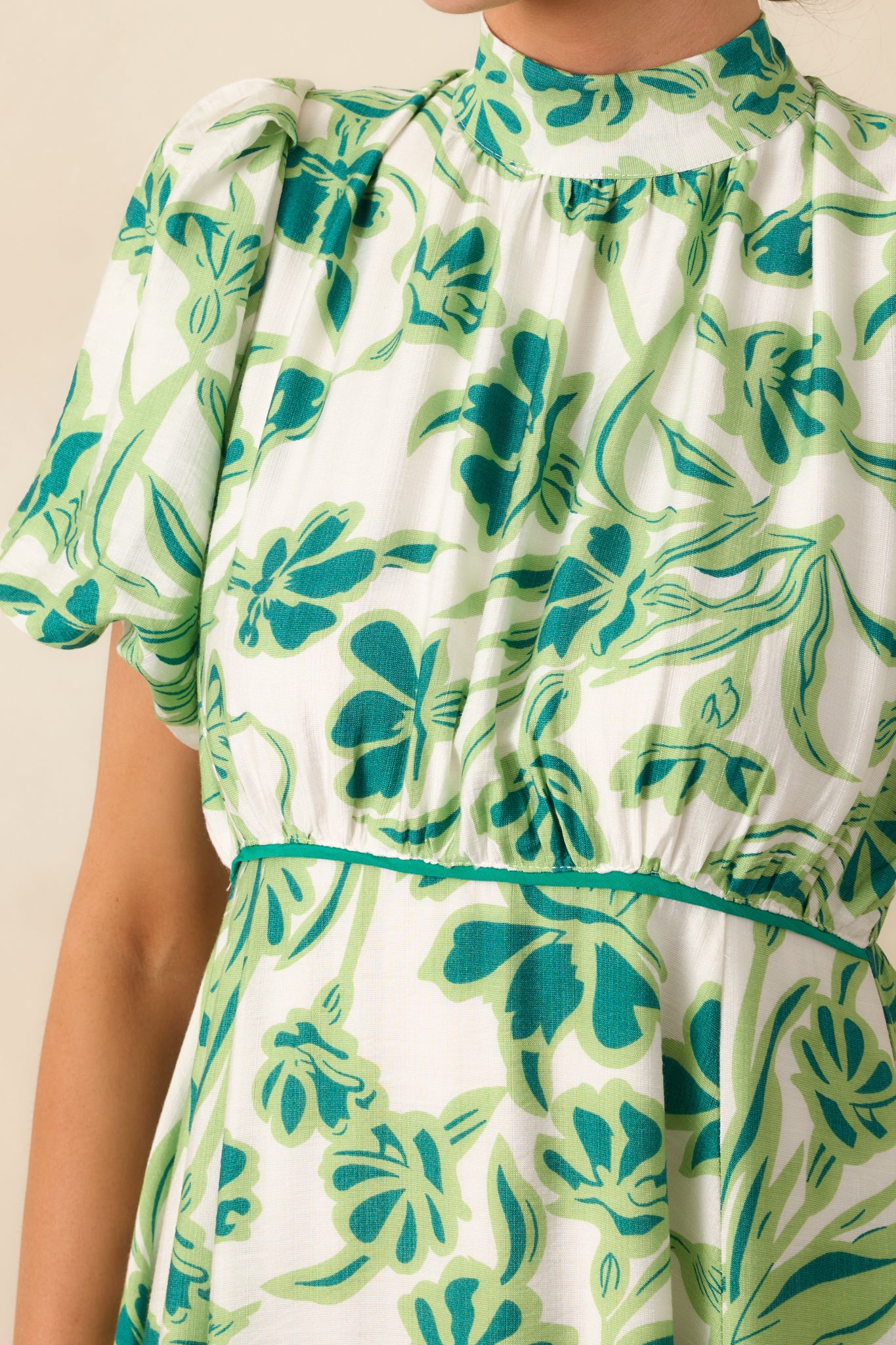 A zoomed-in view of the floral print fabric, highlighting the intricate smocked back detailing and delicate texture of the dress.