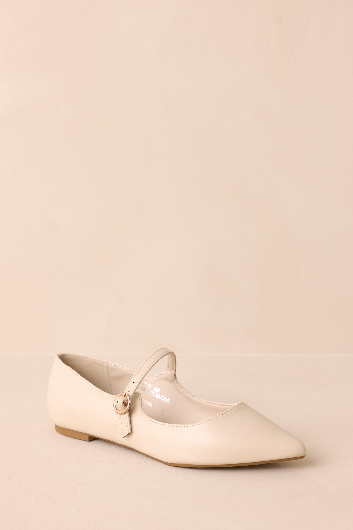 Angled view of ivory flats, showing the side and top details, including the buckle and the cushion in the middle for comfort.