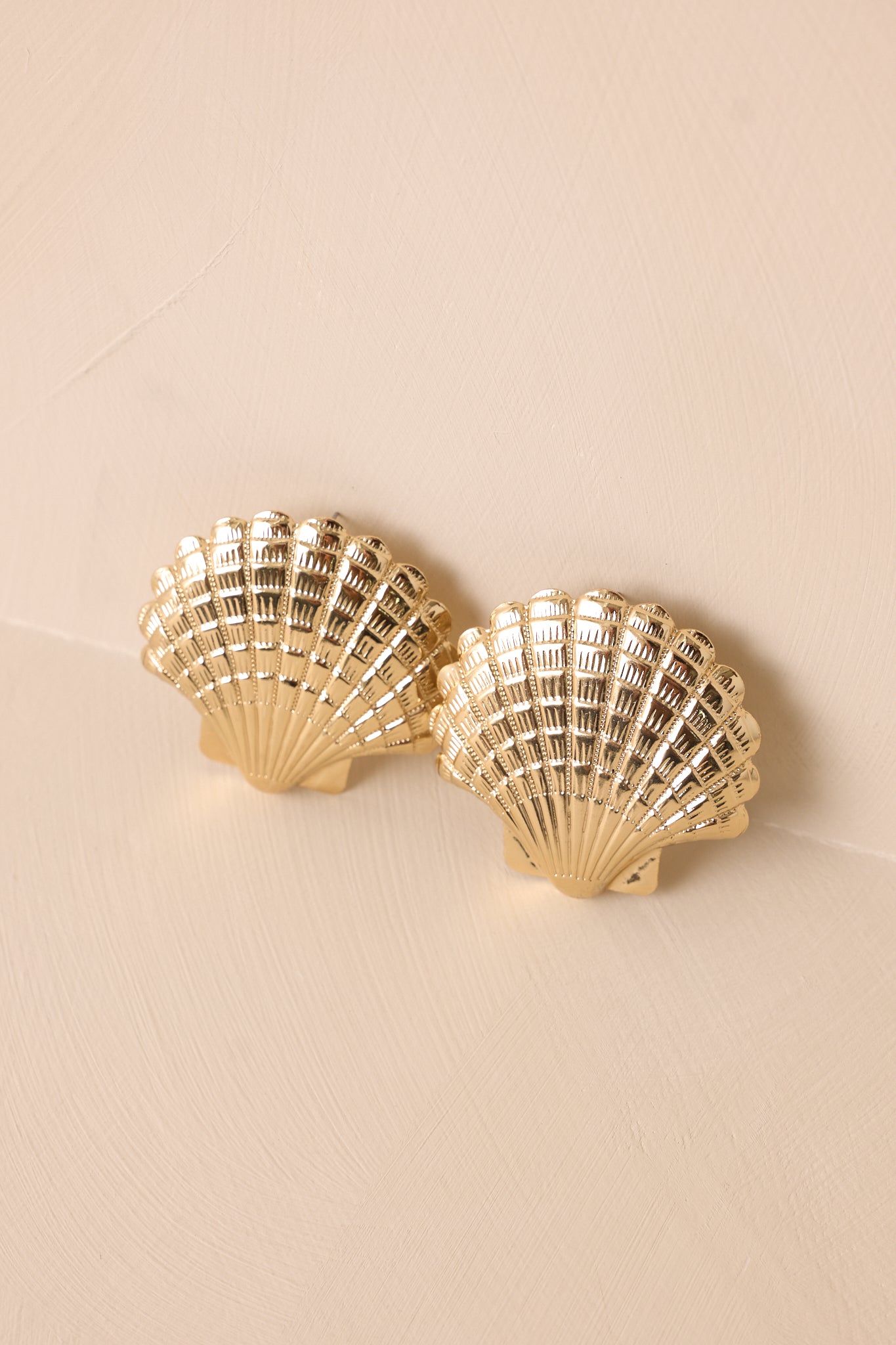 Statement gold seashell earrings with a textured finish, capturing the intricate details of the scallop shell design.