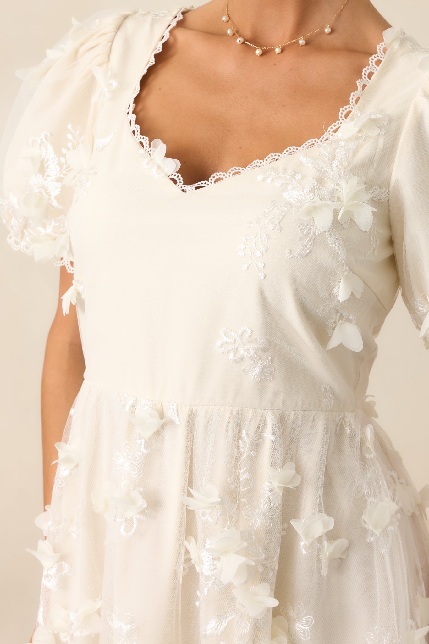 A close-up of the floral applique overlay, showcasing the intricate details and texture that add dimension to the dress.