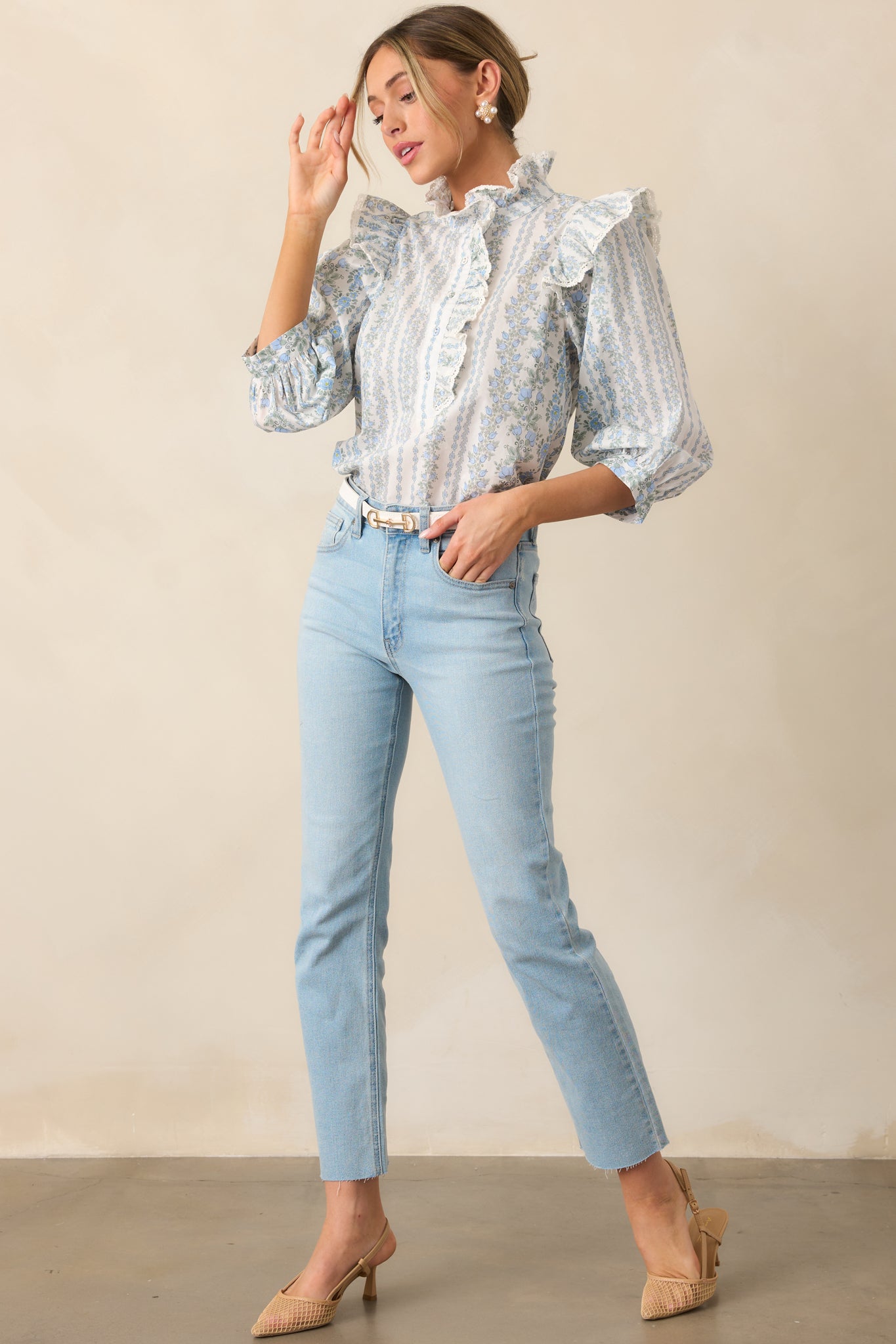 An angled front view of the blue blouse, showcasing its ruffle collar neckline, button front detailing, and relaxed fit.