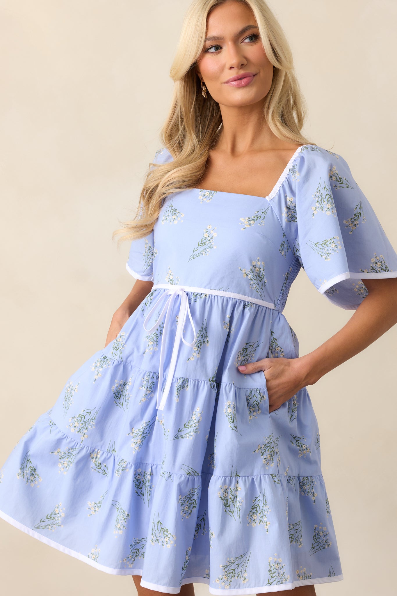 A close-up of the square neckline and butterfly sleeves of the periwinkle floral dress, showcasing the elastic shoulder strap inserts.