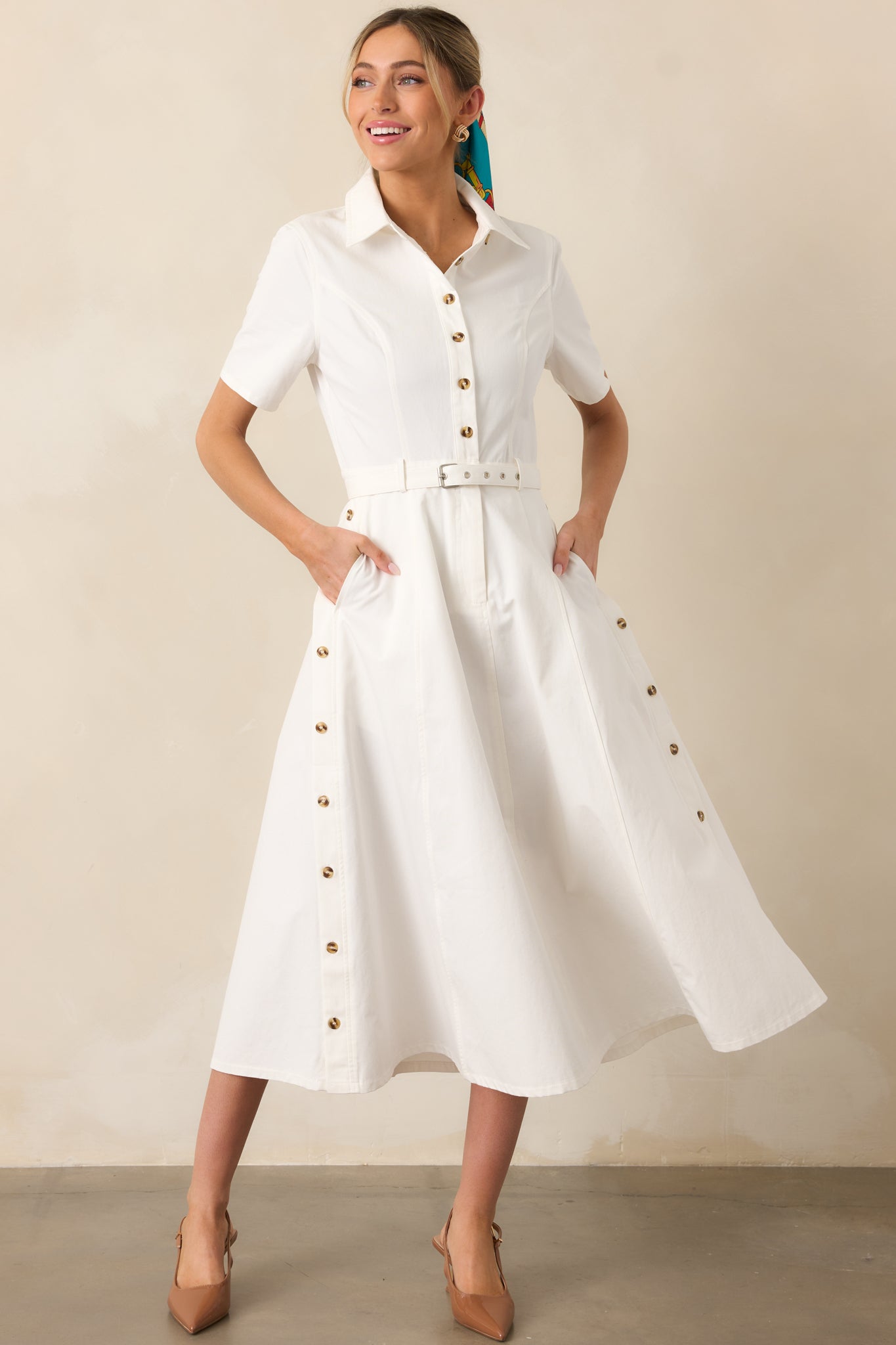  Crisp white dress featuring a structured collar, functional pockets, and nonfunctional side buttons for added detail.