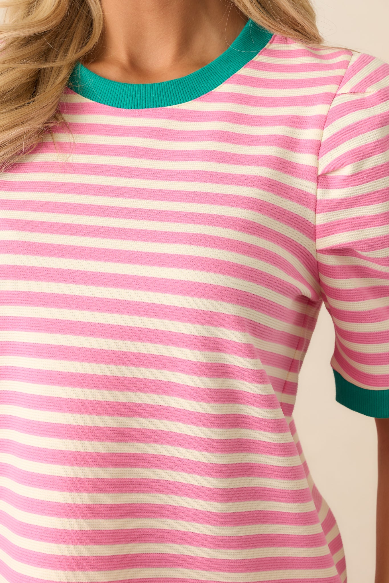 A close-up of the collar trim, showcasing the vibrant green contrast against the pink fabric.