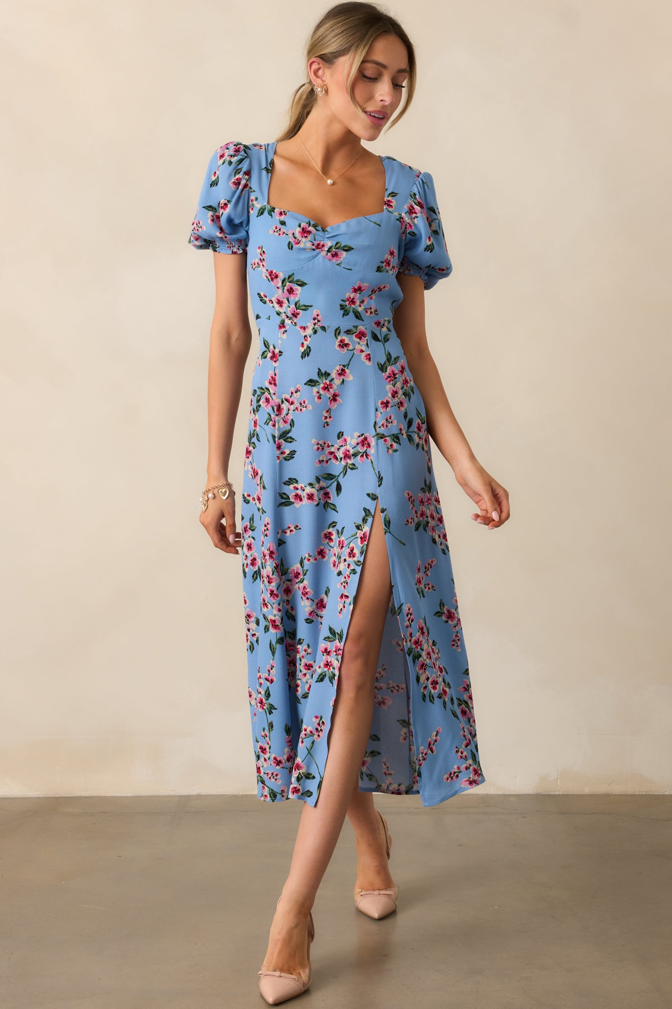An ash blue dress with a romantic sweetheart neckline, short puff sleeves, and a flowing silhouette, complete with a stylish leg slit.