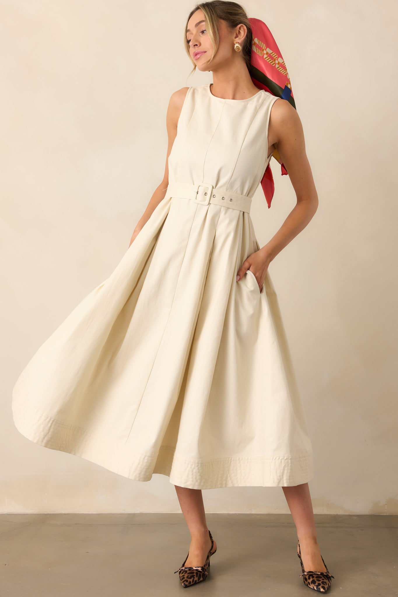  An ecru dress with a rounded neckline, panel stitching, and a belted waistline, creating a structured yet effortless silhouette.