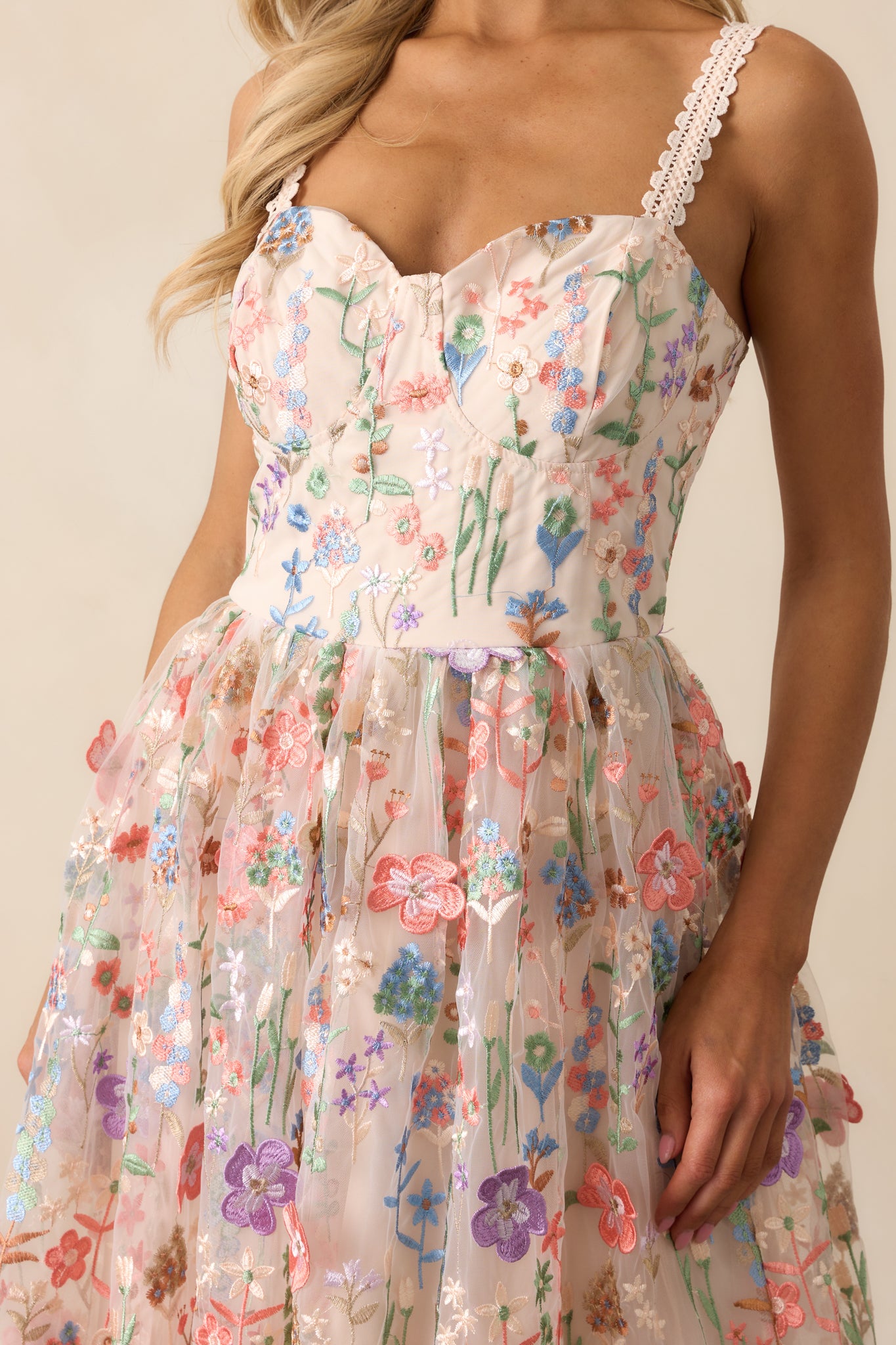 A close-up of the embroidered floral details on the shoulder straps and the sheer floral overlay on the skirt, showcasing the delicate stitching and texture.