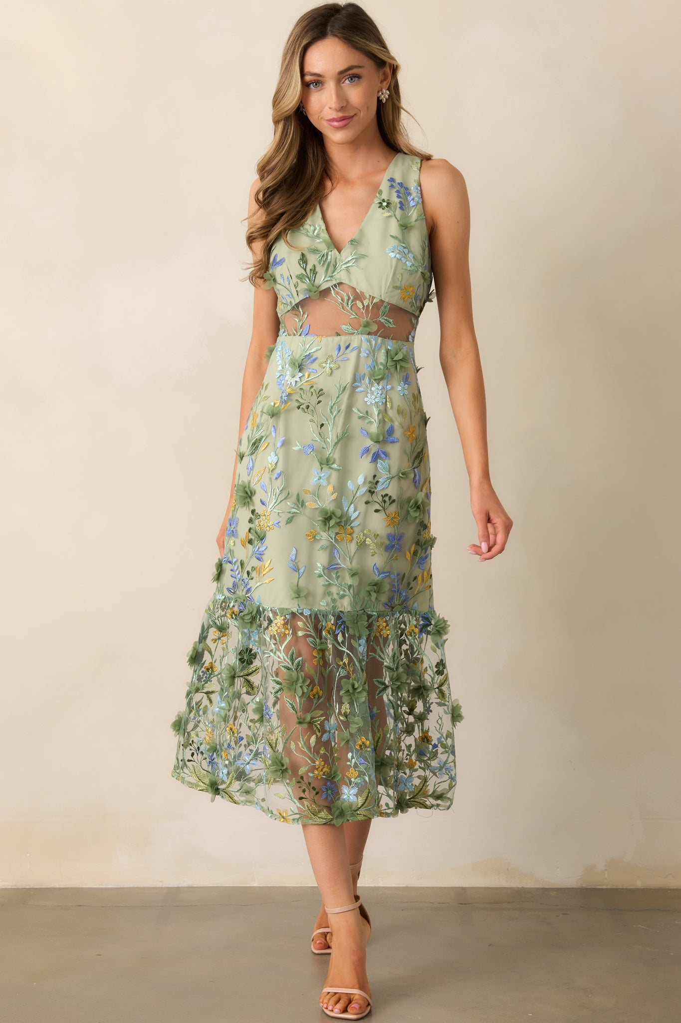 A graceful green midi dress with a v-neckline, sheer waistline detailing, and a beautiful floral embroidered overlay, designed with a mini underlay and sleeveless cut for a chic look.