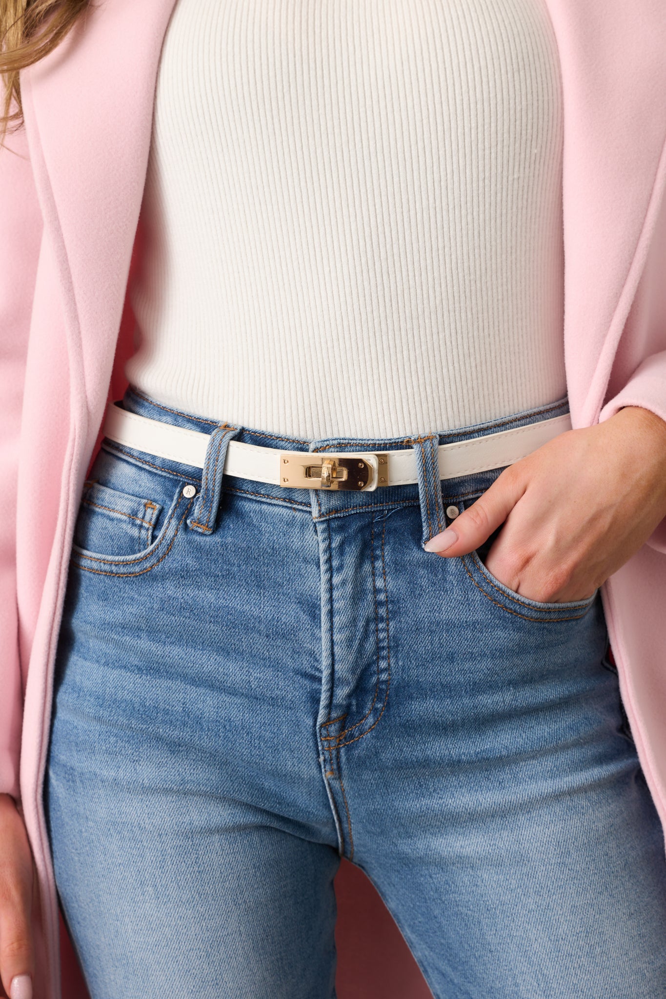 A front view of the ivory belt, showcasing its smooth material and gold twist lock closure.