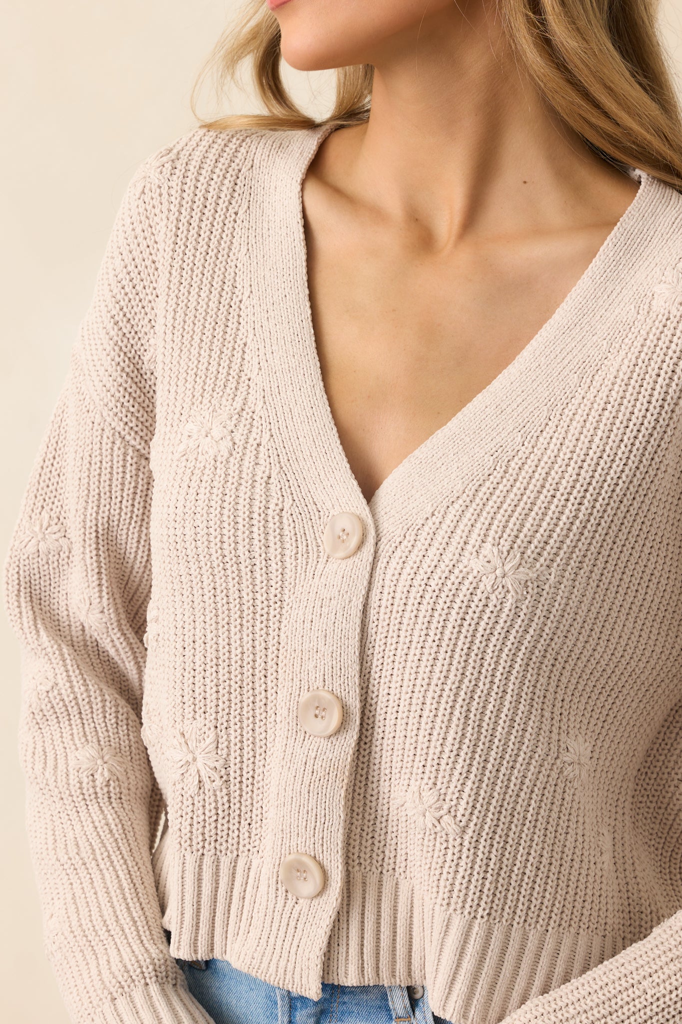 A close-up of the parchment cardigan showcasing its intricate floral embroidery, textured knit fabric, and functional buttons.