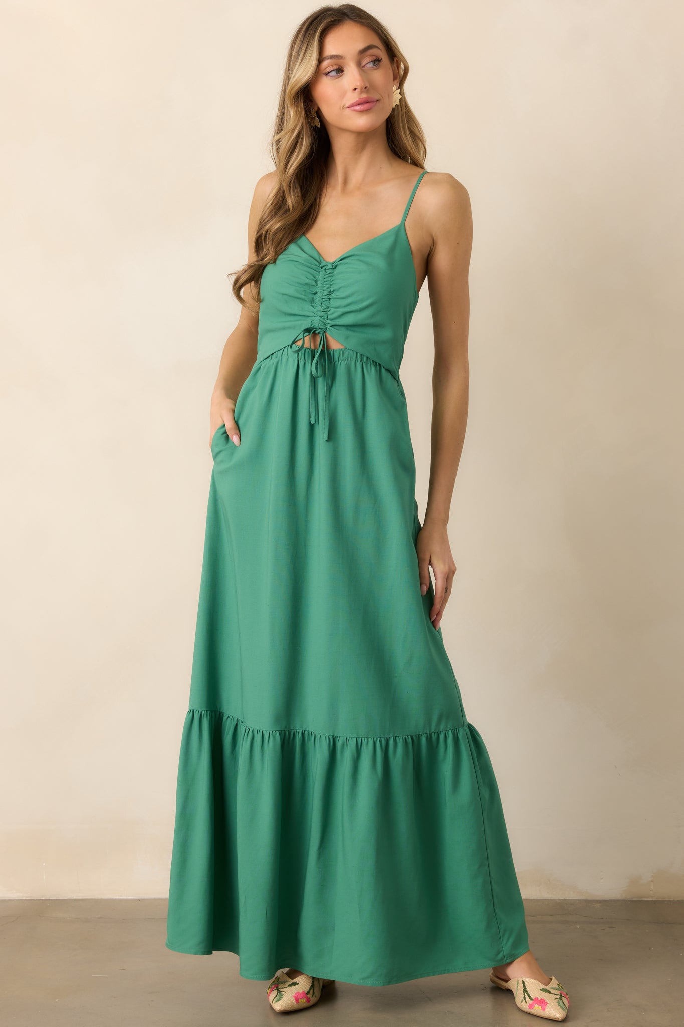 A flowy green maxi dress with a V-neckline, adjustable straps, and a ruched bodice tied neatly at the front.