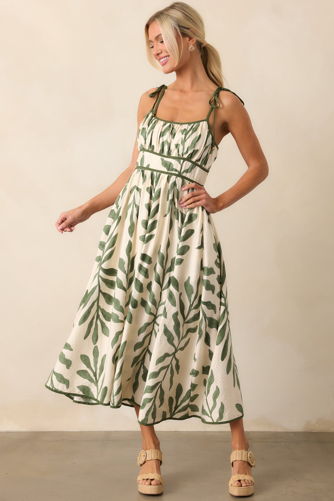 A green midi dress with a rounded neckline, tropical palm print design, and a flowy silhouette for a breezy, effortless look.