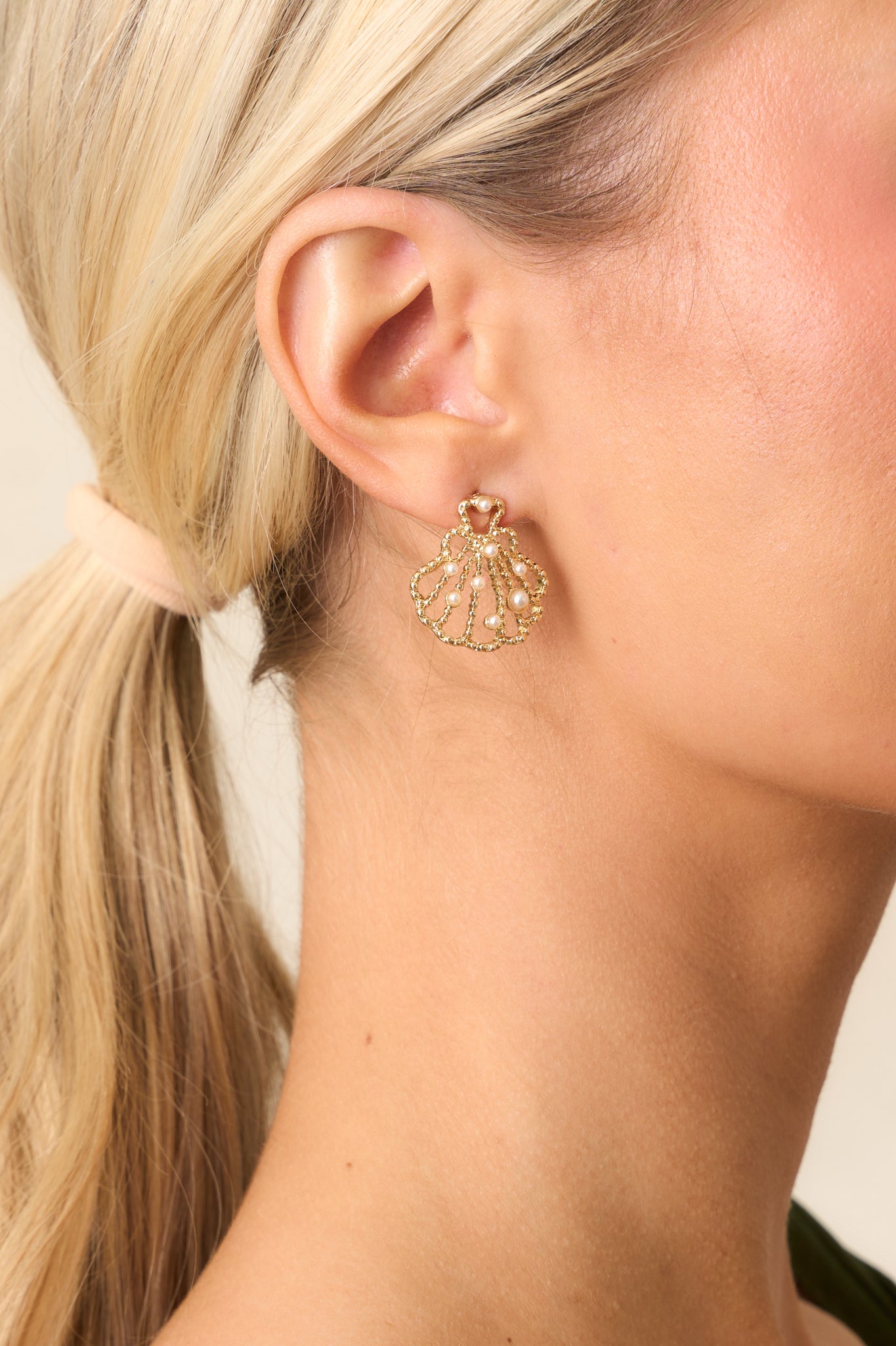 Gold seashell earrings with a stud design, featuring delicate gold beaded wiring throughout and a scallop seashell shape, adorned with small ivory faux pearls.

