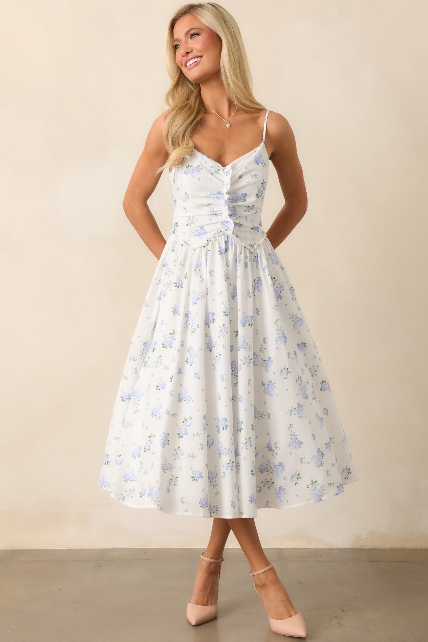 A lovely blue floral midi dress featuring a sweetheart neckline, ruched ruffle detailing along the bodice, adjustable straps, and a hidden back zipper for a sleek, feminine look.