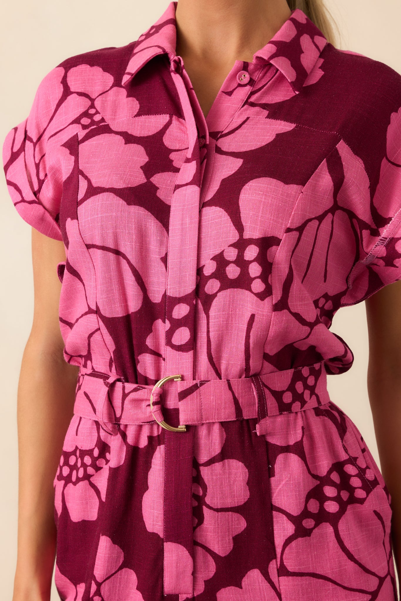 Focused on the gold buckle of the optional belt, emphasizing the cuffed short sleeves, collared neckline, and smooth button front of the playsuit.