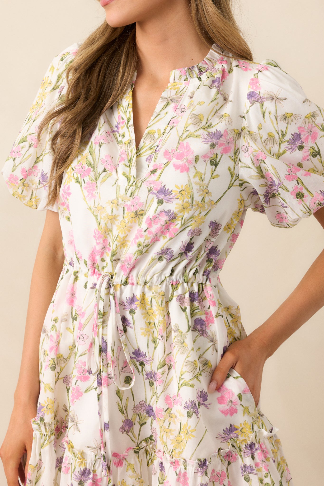 A closer look at the ruffle details and the vibrant pink floral print on the ivory fabric, highlighting the soft texture and feminine touches of the dress.