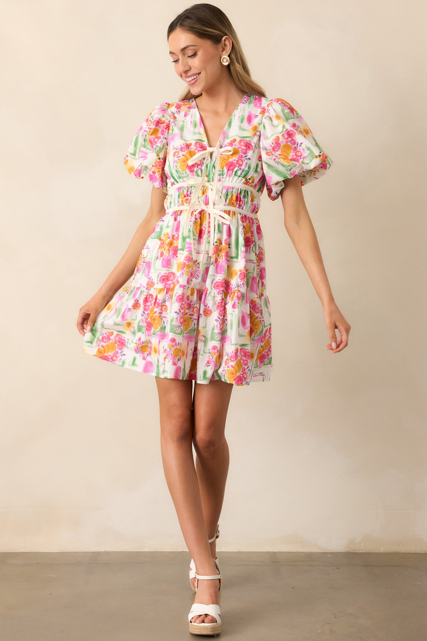 A front-facing view of the pink mini dress, showcasing the v-neckline and tiered skirt in a playful silhouette.
