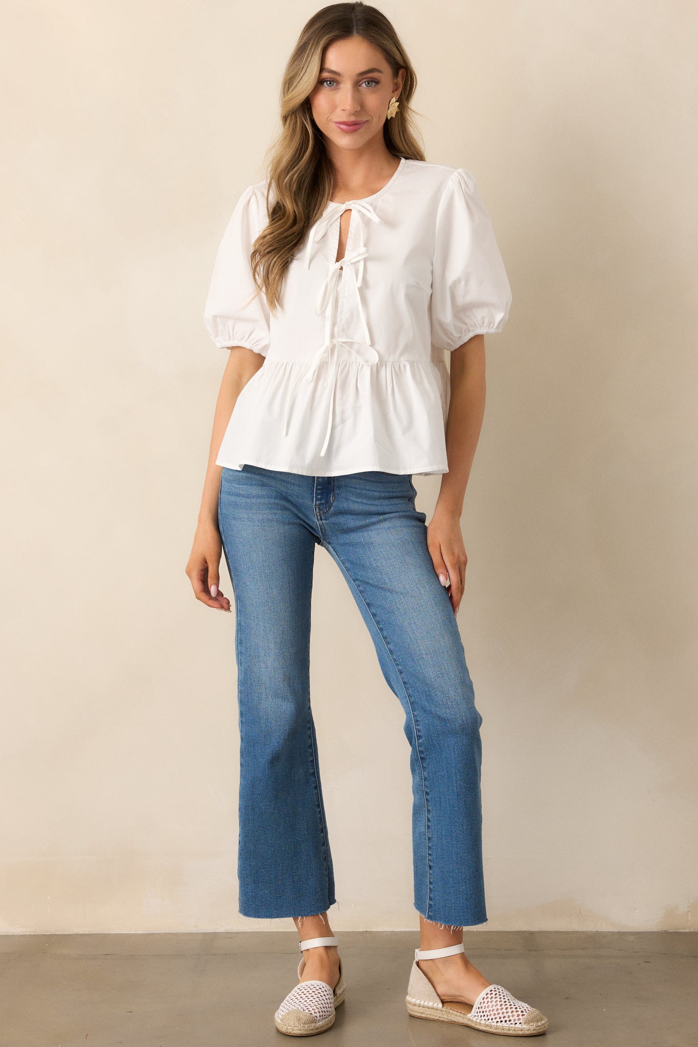 The medium wash jeans in a full-length shot, featuring a button zipper closure, functional pockets, and a flared leg.