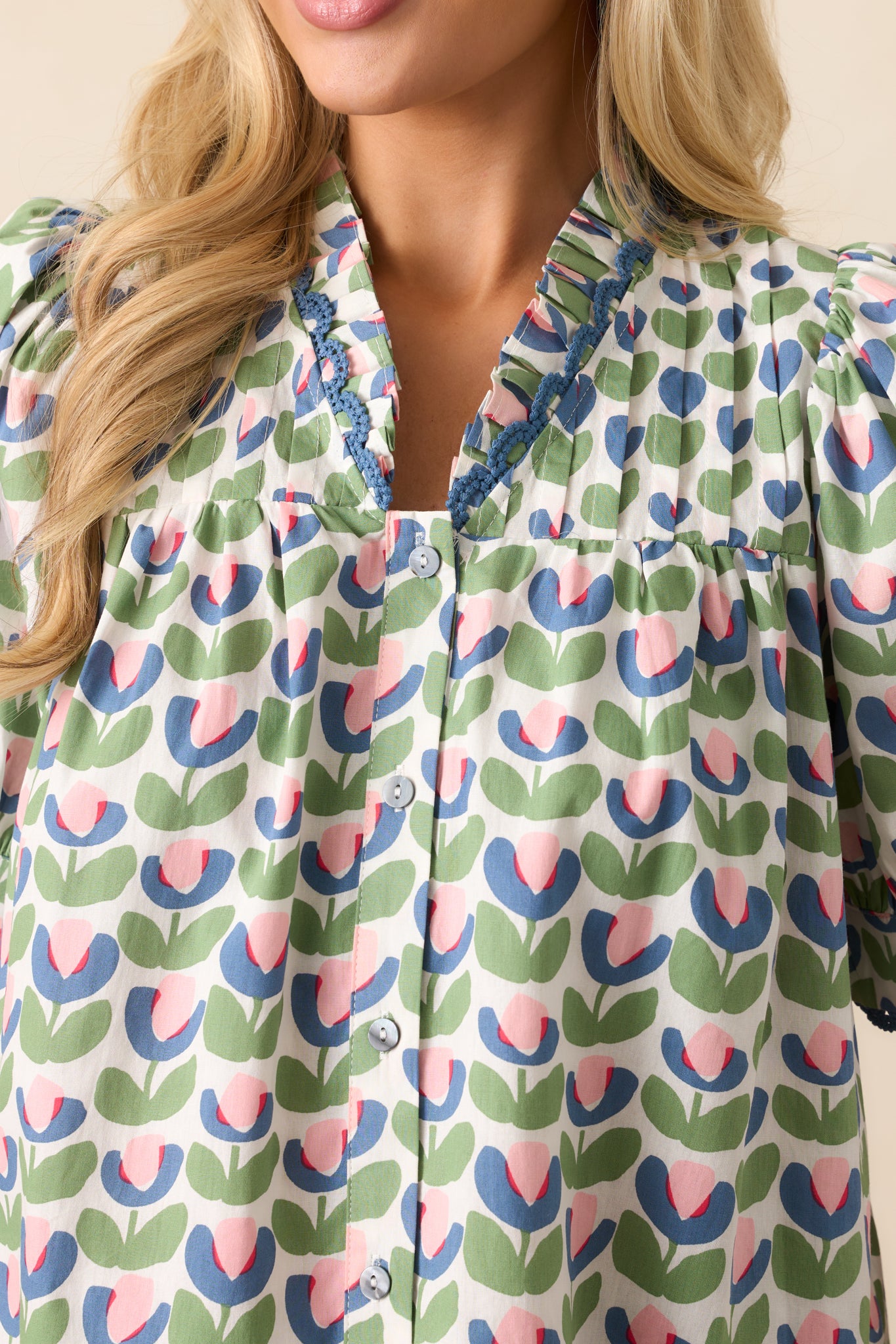  A detailed view of the embroidered sleeve trim, showing the delicate craftsmanship that enhances this green blouse.