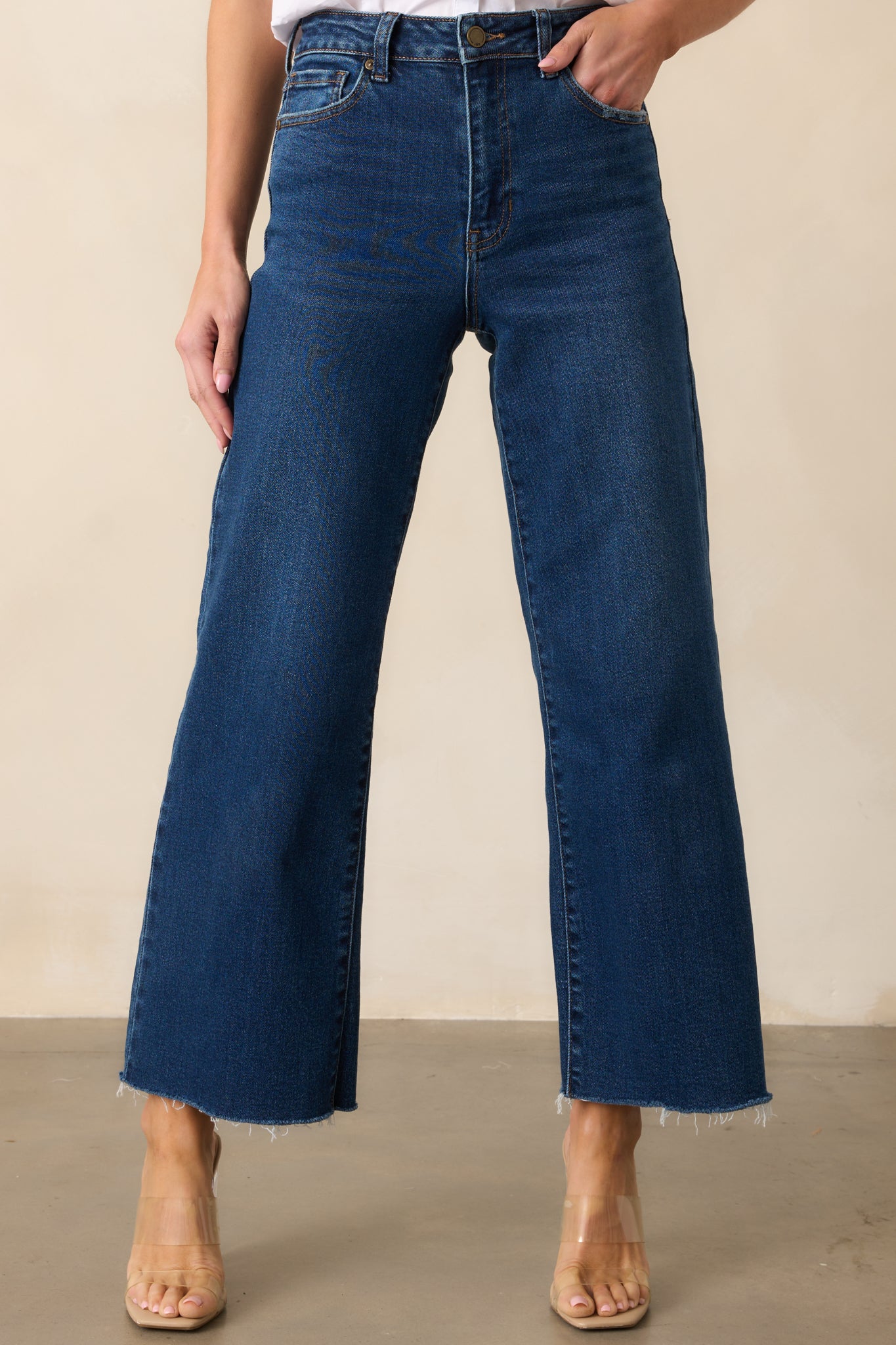 A closer look at the wide leg design of these dark wash jeans, highlighting the raw hem and functional pockets.