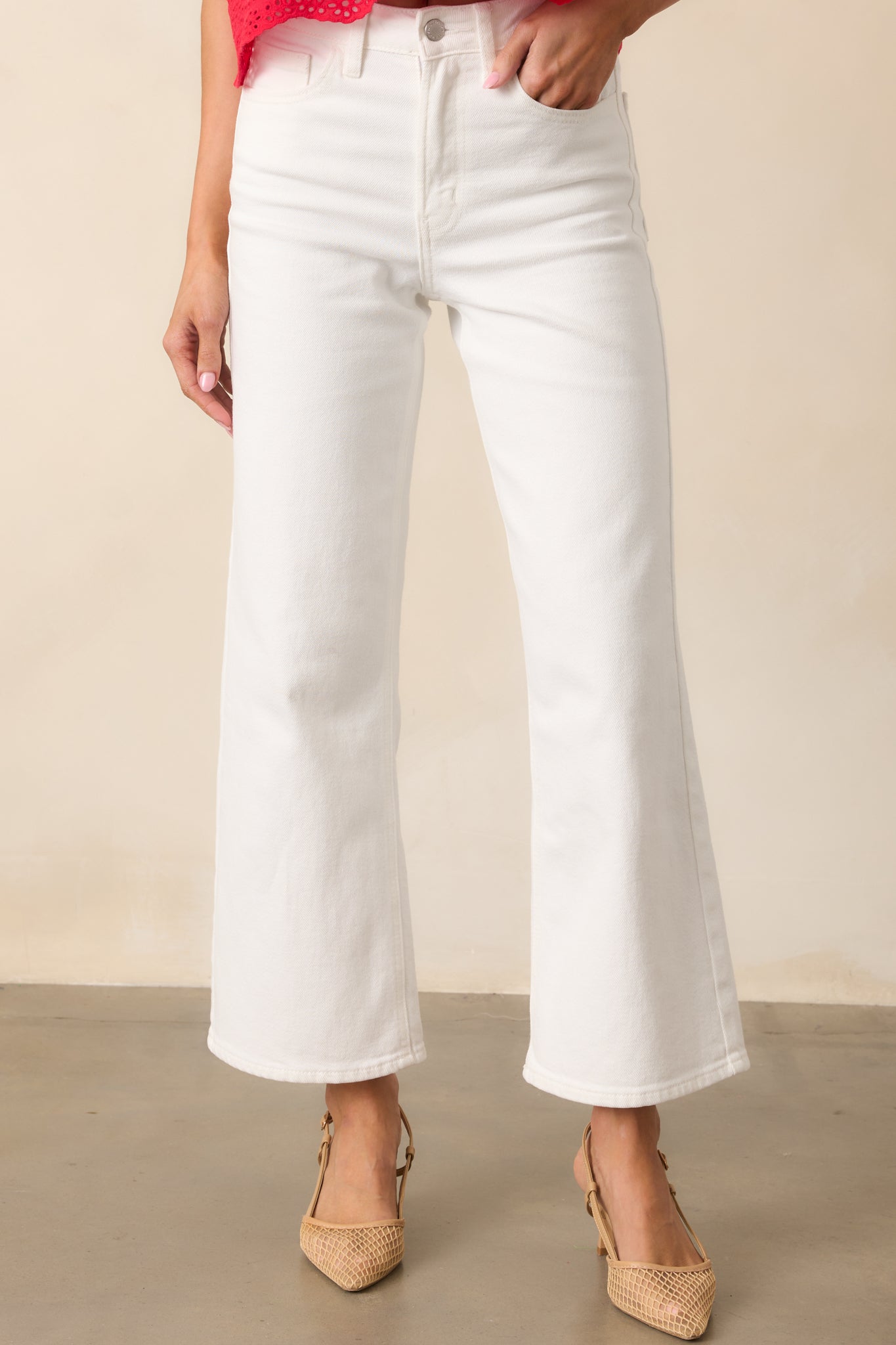 A detailed view of the button and zipper closure, with a closer look at the functional pockets and smooth fabric of the white high-waisted jeans, showing off the clean, crisp design.

