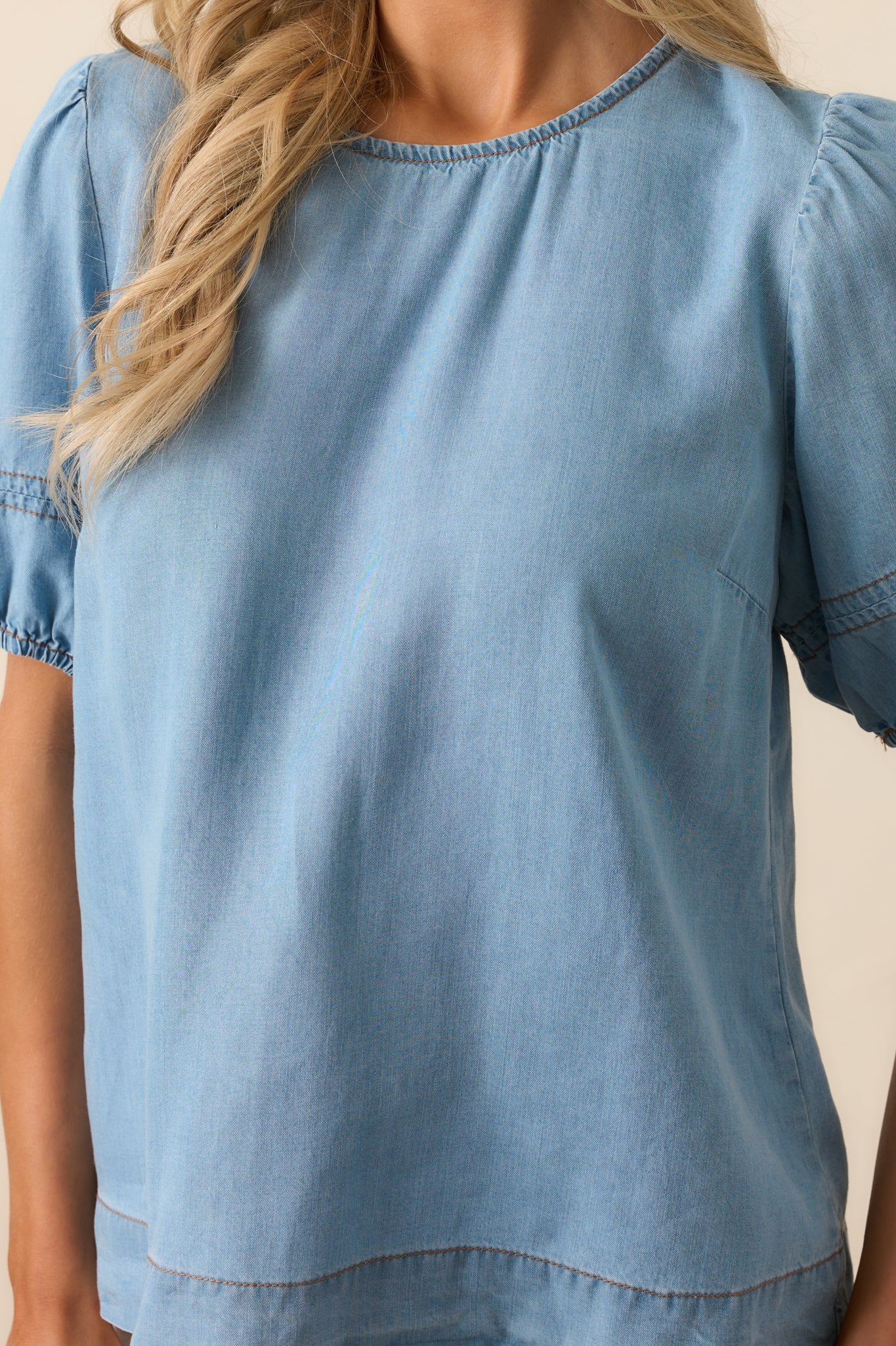 A detailed view of the tan stitch detailing on the puff sleeves, adding a subtle yet stylish touch to the top.