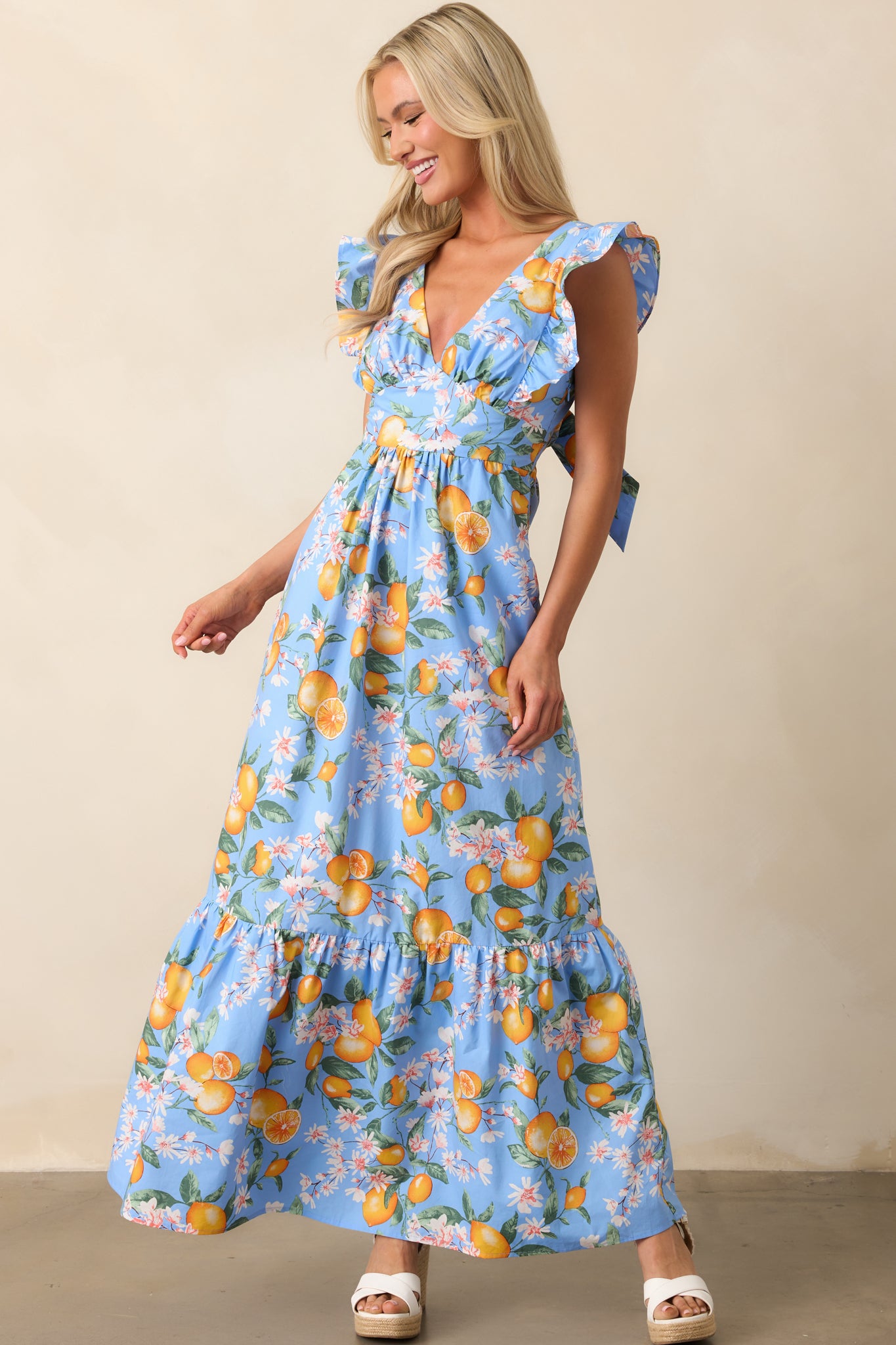 This flowing blue dress showcases a floral lemon print, deep V-neckline, and functional pockets, designed for both style and comfort.