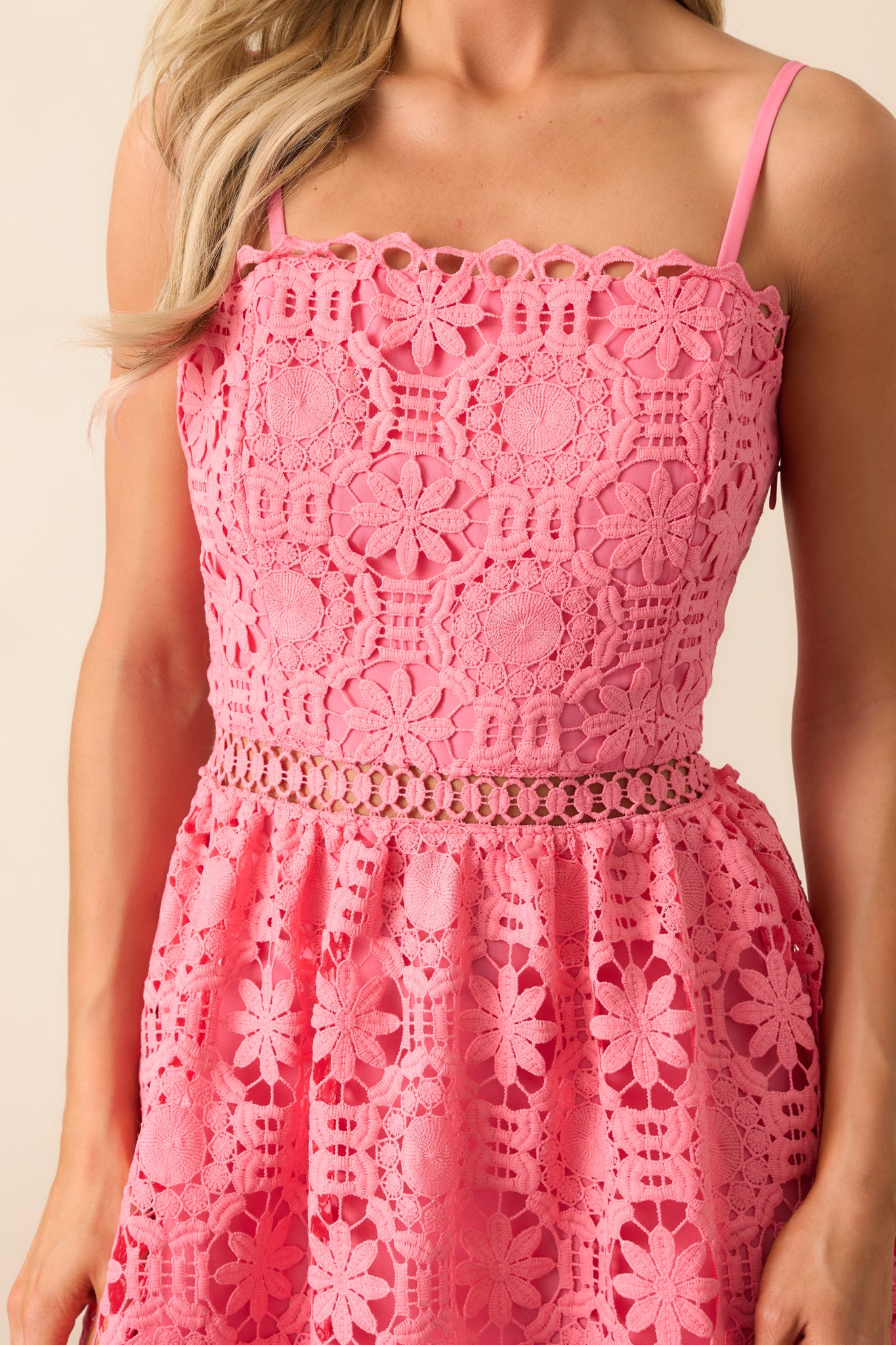 A detailed view of the intricate floral embroidered overlay, highlighting the texture and delicate design that adds a romantic touch to this pink coral dress.