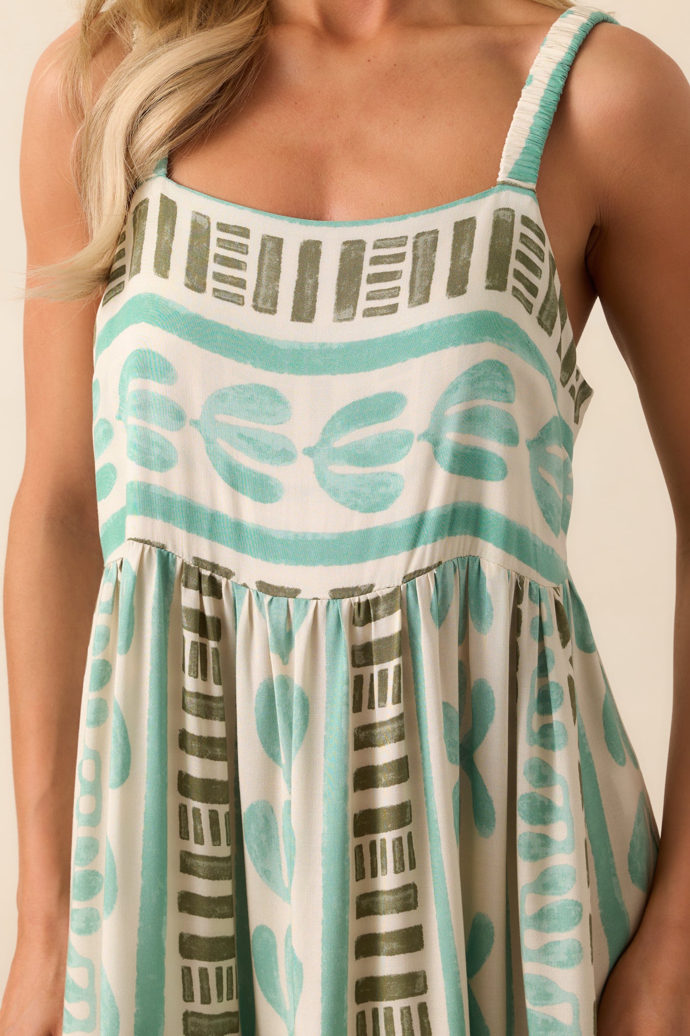 A closer look at the seafoam green dress’s elastic ruched straps and square neckline, highlighting the soft fabric and delicate texture.