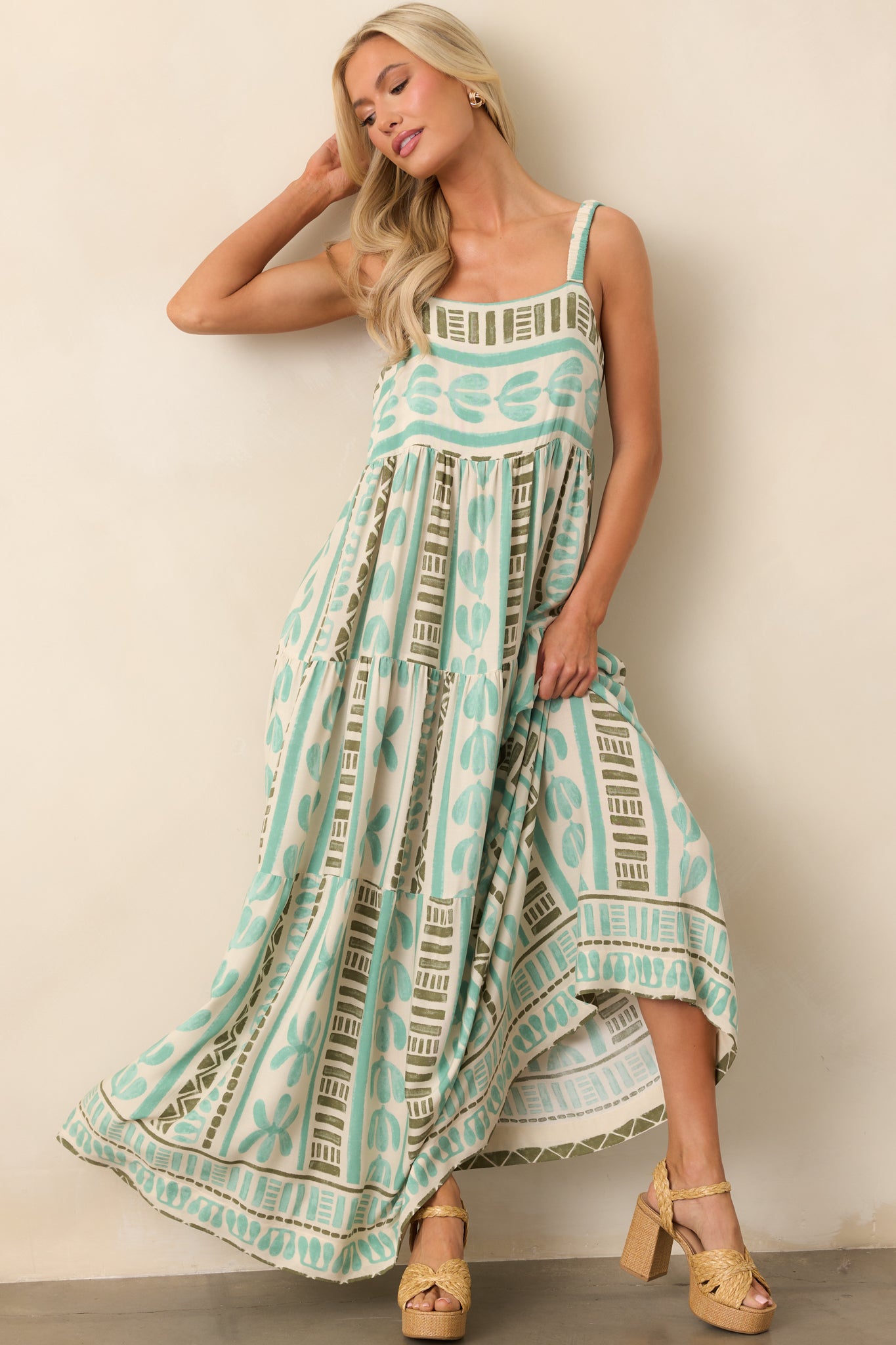 A seafoam green dress with elastic ruched straps and a square neckline, flowing into a tiered skirt with functional pockets.