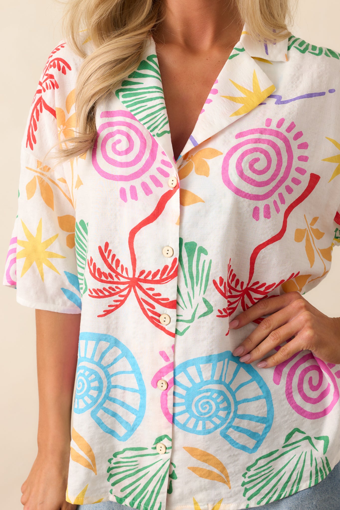 A close-up of the fabric texture, showcasing the intricate tropical print and polished button details.