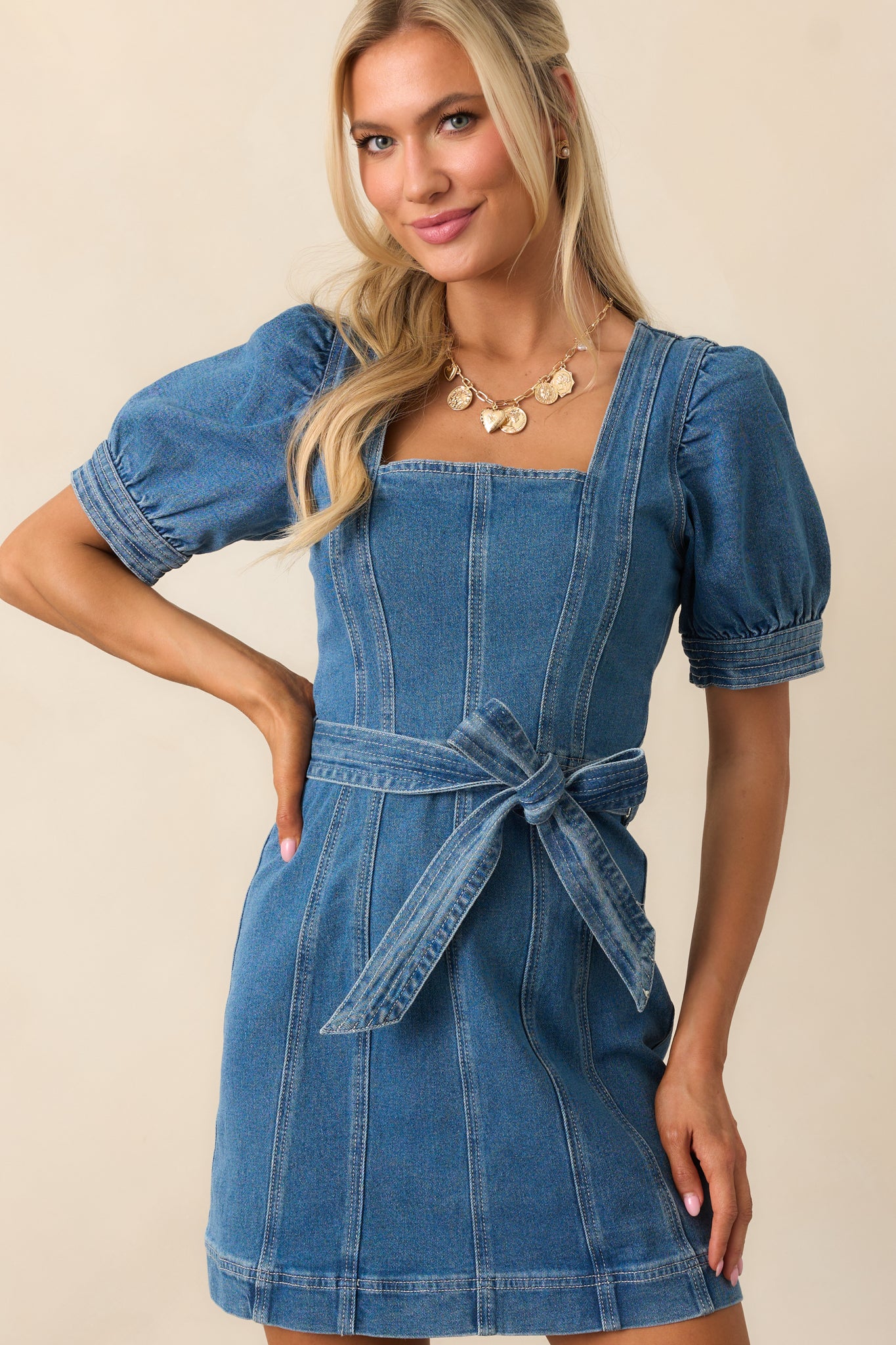 Detail of the panel design on the denim mini dress, emphasizing the structured seams and tailored shape for a polished look.