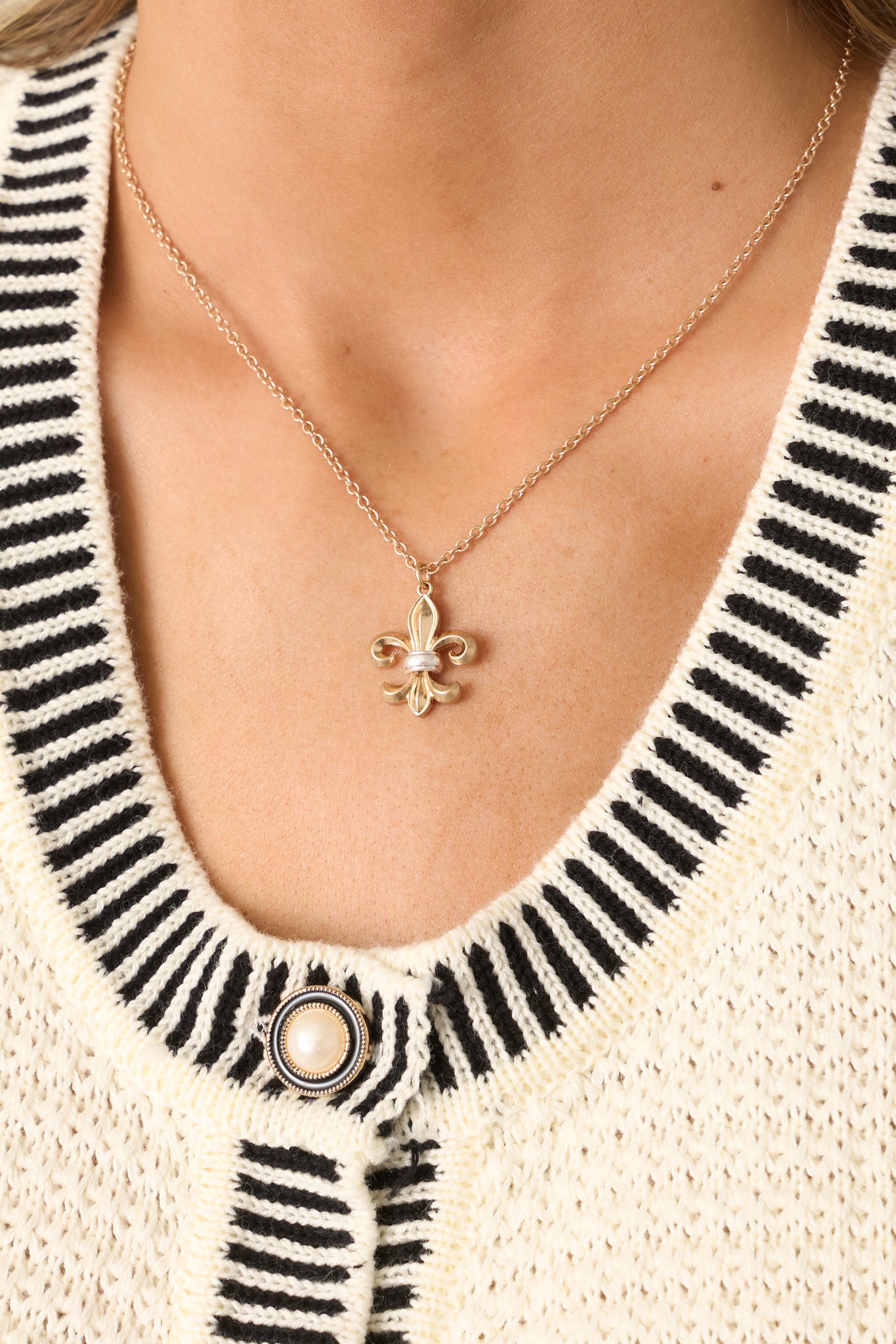 A zoomed-in look at the fleur-de-lis pendant, showcasing its elegant shape, smooth gold surface, and fine craftsmanship.