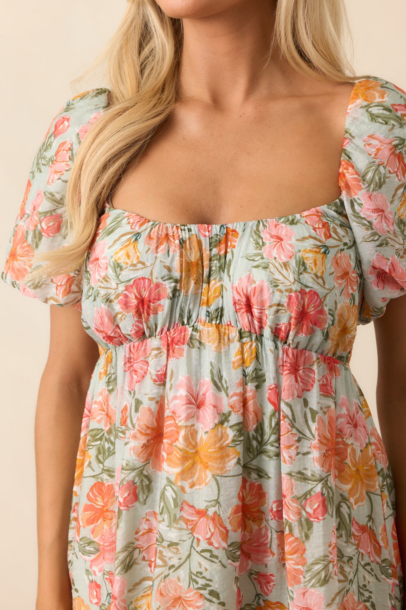 A close-up of the hibiscus floral print and smocked back panel, showcasing the delicate design and thoughtful detailing of the coral mini dress.