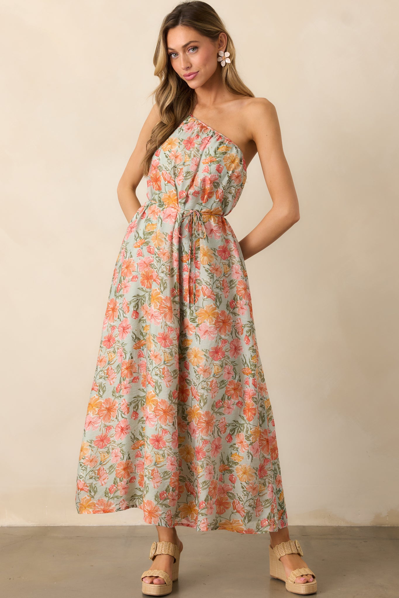 A flowy coral maxi dress featuring a one-shoulder neckline with an adjustable strap, creating an elegant and asymmetrical silhouette.