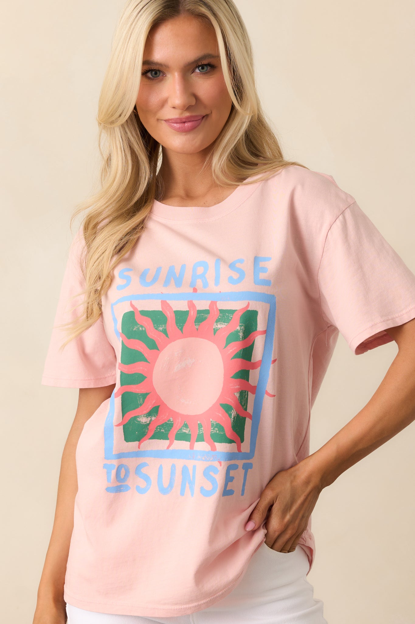 A pink tee with a rounded crew neckline and a relaxed fit, featuring the "Sunrise To Sunset" graphic for a laid-back, casual vibe.