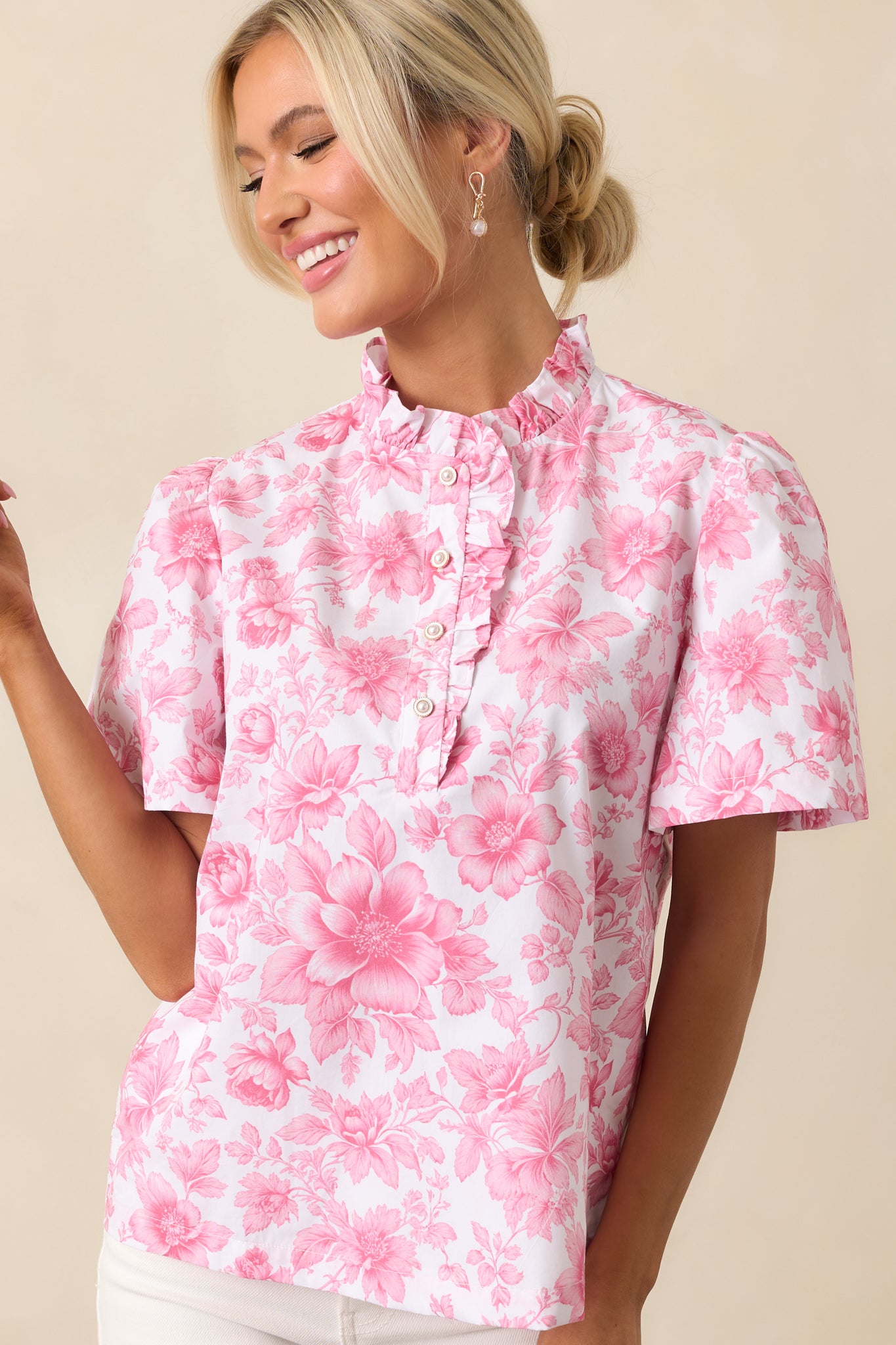 The high ruffle neckline and short sleeves of this pink top create a sophisticated silhouette, enhanced by the ivory faux pearl buttons.