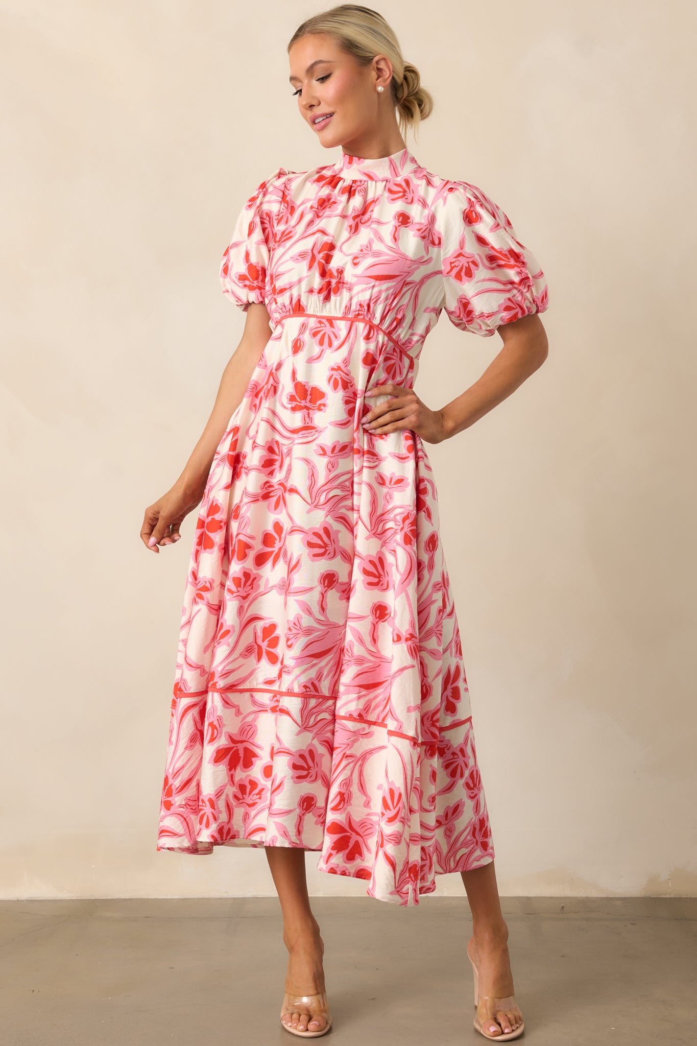 A pink midi dress with a high self-tie mock neckline, a delicate floral print, and soft puff sleeves.