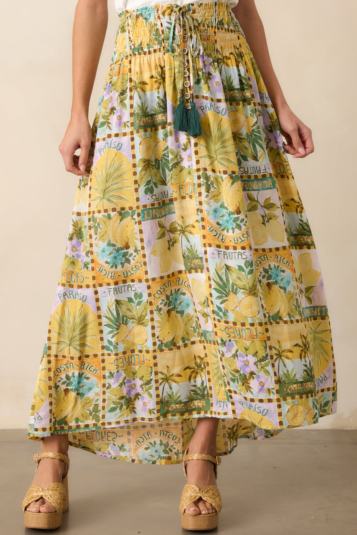 Zoom in on the intricate details of the self-tie waist with green tassels and the wide smocked waistband, adding to the effortless style of this tropical print maxi skirt.