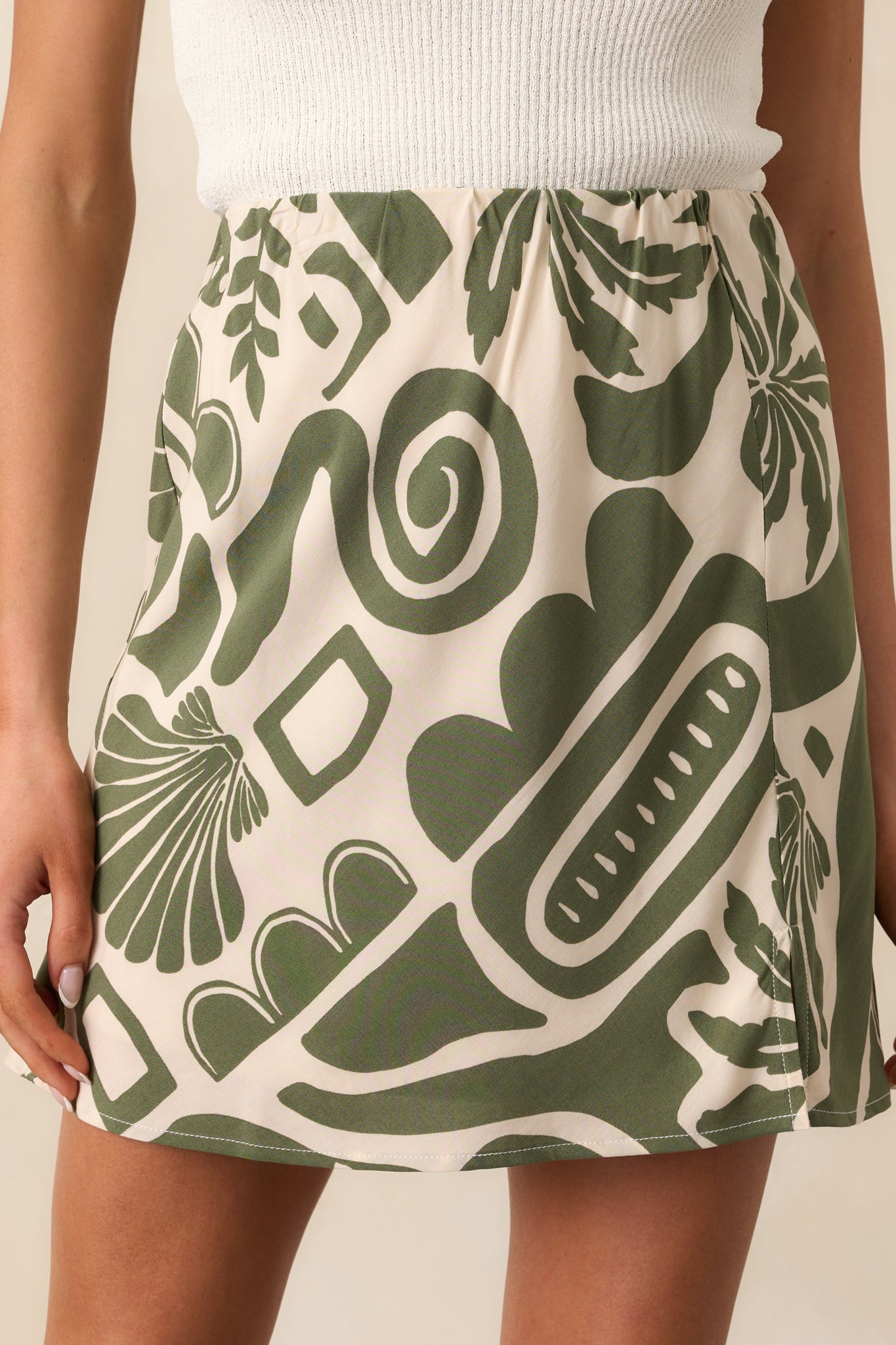 The intricate tropical pattern on the green skirt, showcasing ivory-toned leaves against the lightweight fabric.