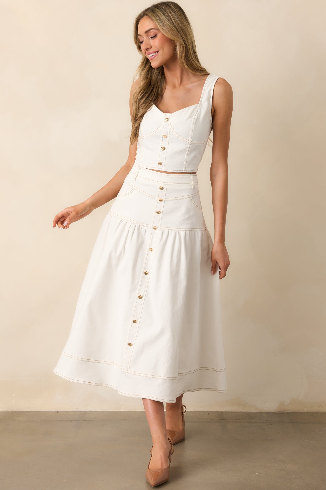 A crisp white denim maxi skirt with a streamlined drop waist and a flattering high-rise fit.