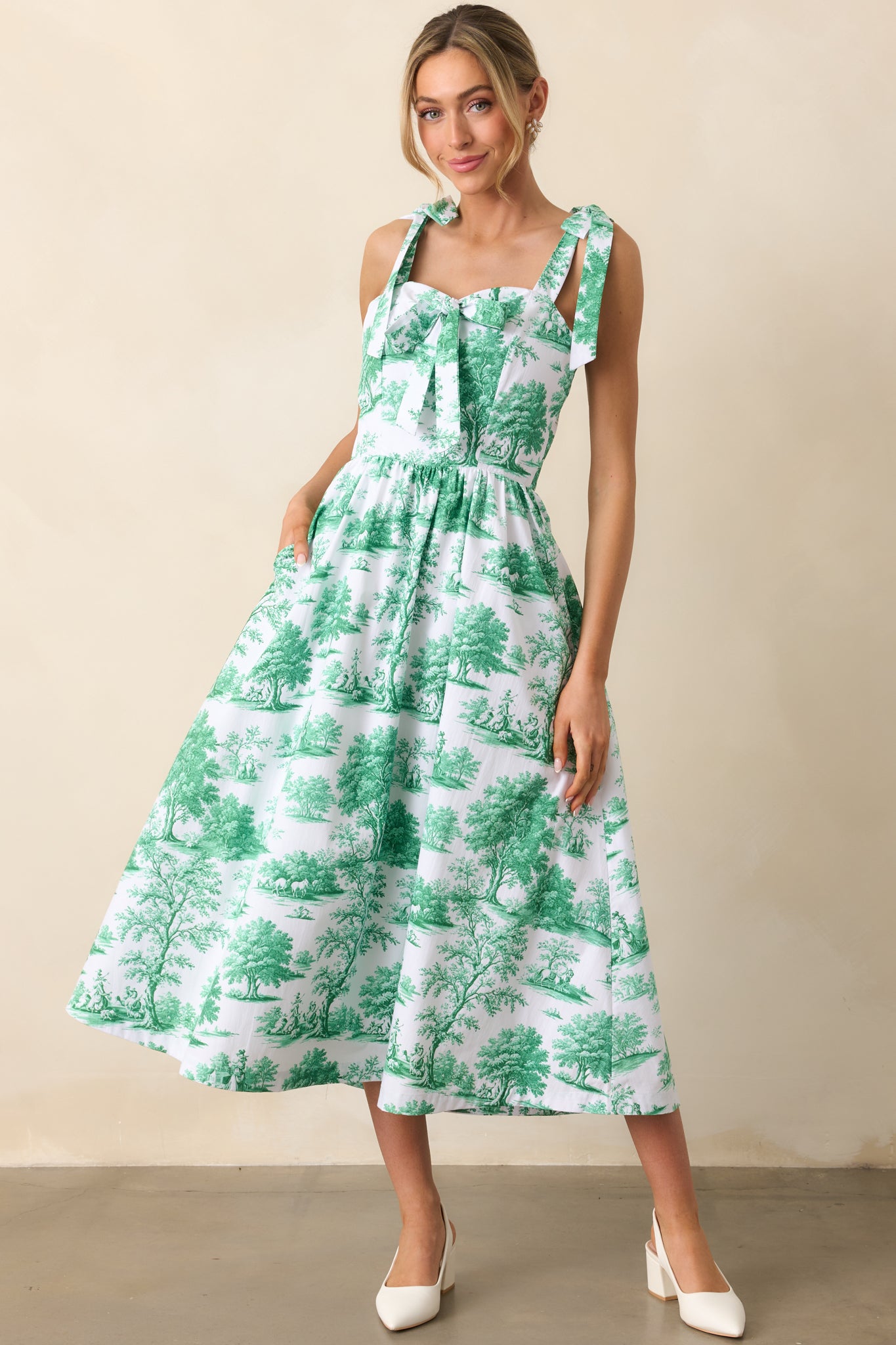 An eden green midi with soft bow accents, a smocked rear panel for comfort, and hidden pockets seamlessly blended into the design.