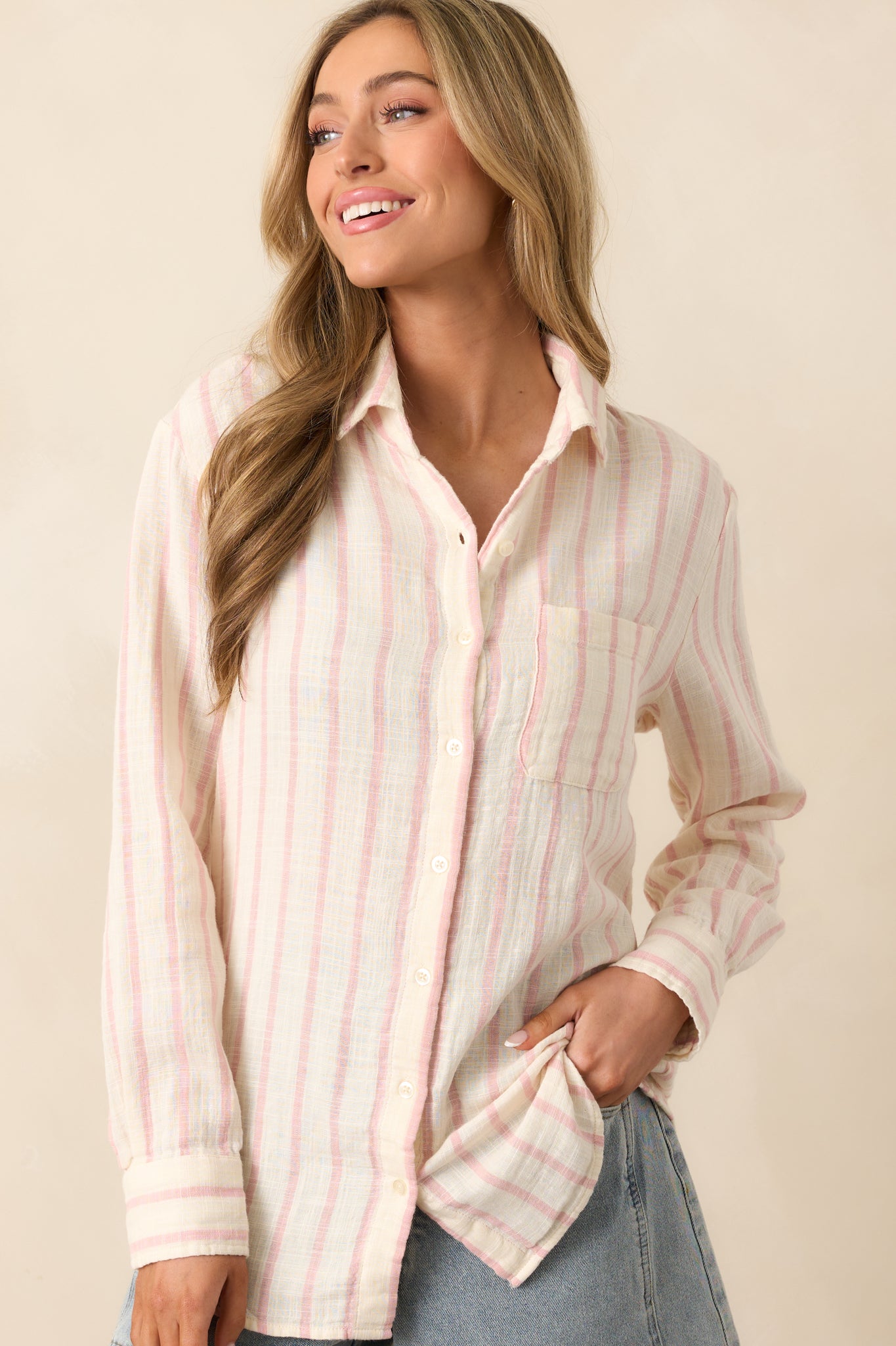 A detailed shot of the long sleeves and button cuffs on this ivory top, emphasizing the light pink stripes and breathable cotton gauze fabric for a soft and relaxed fit.