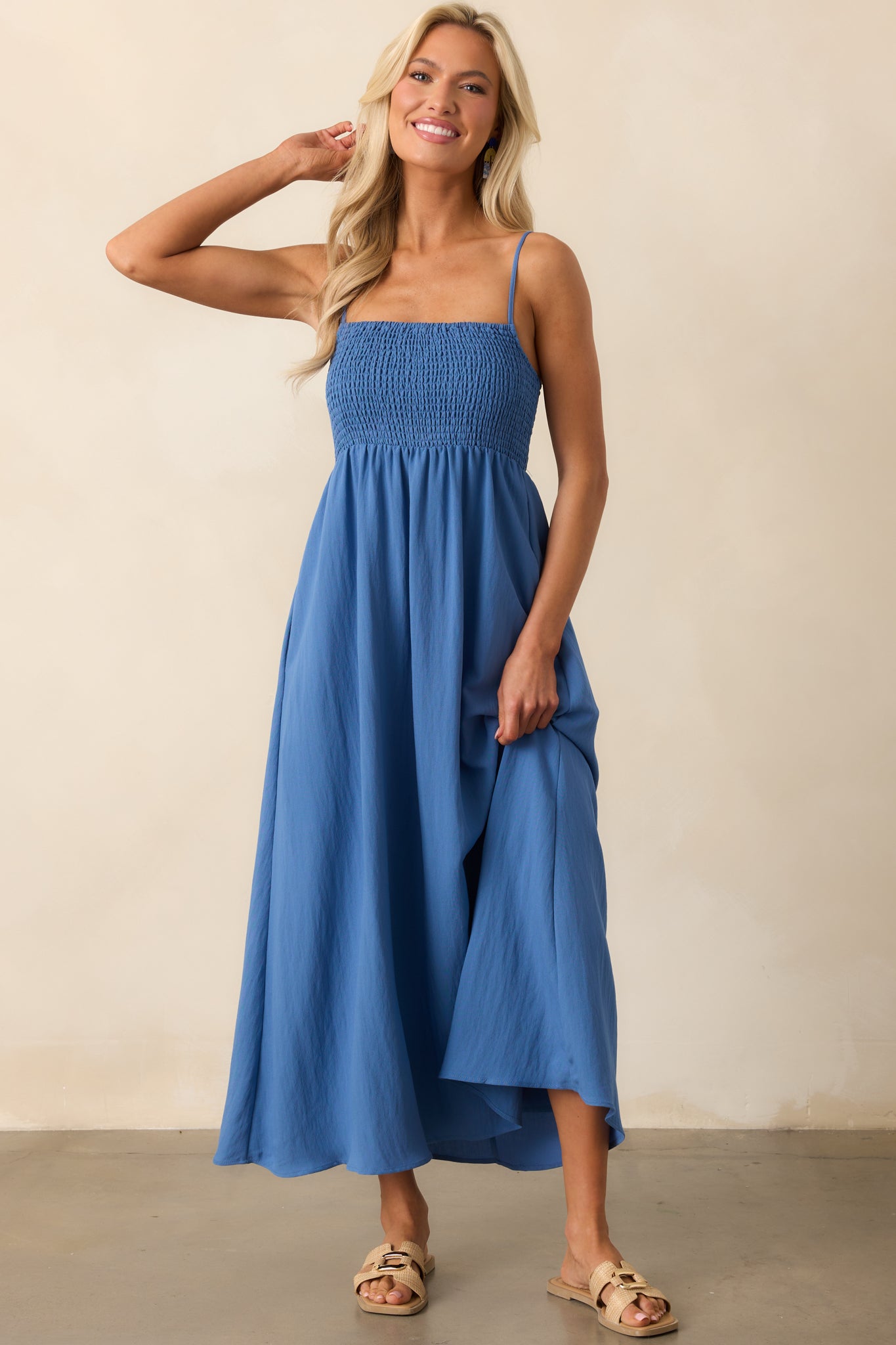 A riviera blue dress with a square neckline and a fully smocked bust, featuring adjustable spaghetti straps for a customized fit and a flattering midaxi length.