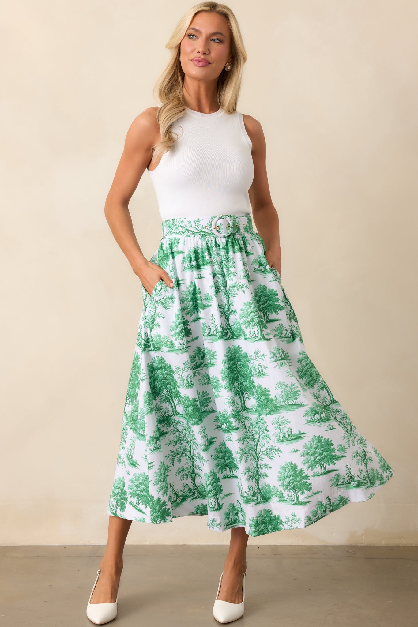 An eden green midi skirt featuring a delicate toile print, an elastic waist insert for a comfortable fit, and functional pockets for added convenience.

